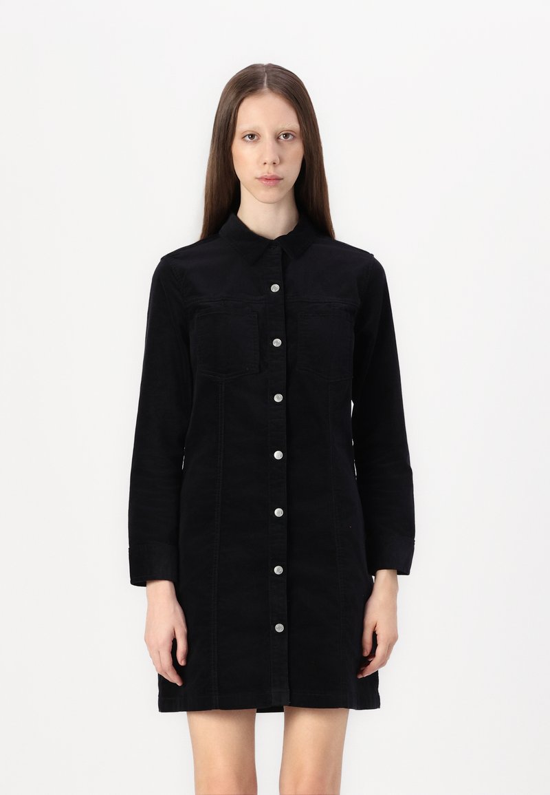 Black denim shirt dress with long sleeves, button front, two chest pockets, and subtle stitching details. Smooth fabric texture.