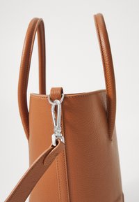 Brown textured leather handbag with two rounded handles, a detachable strap, and a metal clip for securing the strap.