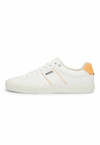 Zapatillas de cuero blancas con acentos naranjas, que cuentan con una suela de goma texturizada y un branding sutil en el lateral. Diseño de perfil bajo, forma clásica.