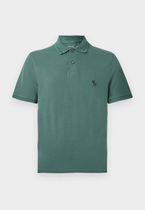 Camiseta polo de algodón verde con cuello, dos botones y un pequeño logo negro en el pecho. Manga corta y dobladillo recto.