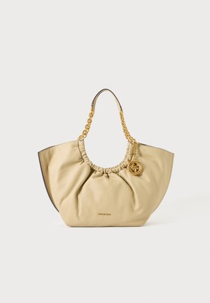Beige weiche Lederhandtasche mit goldenen Kettengriffen und einem runden goldenen Logoanhänger, der subtile geraffte Details an der Öffnung zeigt.