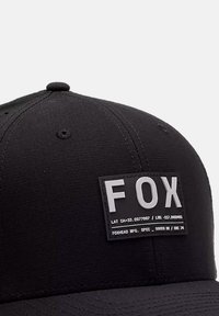 Schwarze Baseballmütze aus strukturiertem Stoff, mit einem rechteckigen Patch, auf dem das Wort "FOX" in fetten weißen Buchstaben steht.