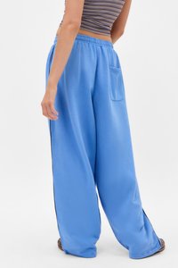 Calças largas de tom azul claro feitas de material macio, com cintura elástica, um bolso traseiro e detalhes laterais em preto.