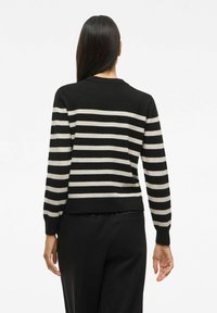 Zwart en beige gestreepte trui met lange mouwen en een ronde hals, met een getailleerde pasvorm en geribde manchetten.