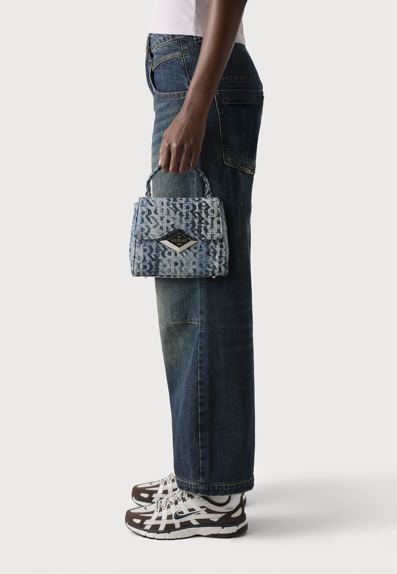 Borsa in denim dalla forma strutturata, con un motivo a logo blu e bianco, un emblema a forma di diamante e una maniglia superiore per il trasporto.