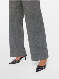 Schwarze Slingback-Pumps mit weißen Punkten und spitzen Zehen, kombiniert mit grauen Hosen mit weitem Bein aus einem strukturierten Stoff.