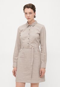 Abito di velluto a coste beige con colletto, chiusura davanti con bottoni, maniche lunghe, cintura in vita e due tasche. Tessuto testurizzato.