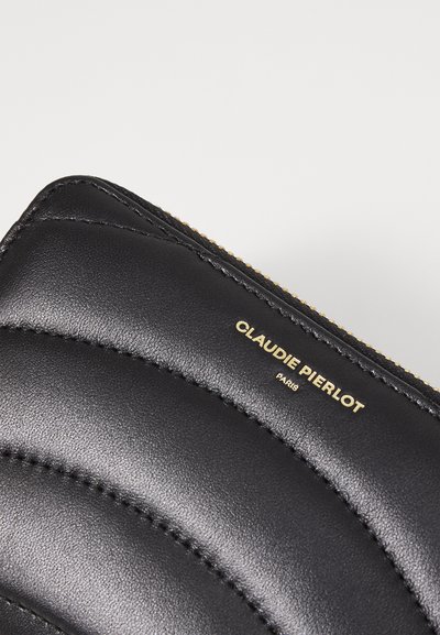 Cartera de cuero negro con patrón acolchado, cremallera dorada y logo en relieve "CLAUDIE PIERLOT PARIS." Textura suave y diseño elegante.