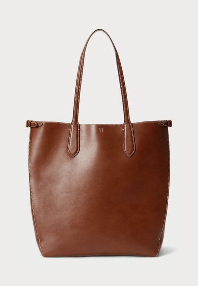 Bruine leren totebag met twee verlengde handvatten, een gladde textuur en een eenvoudig ontwerp. Bevat donkere stiksels en geen zichtbare hardware.