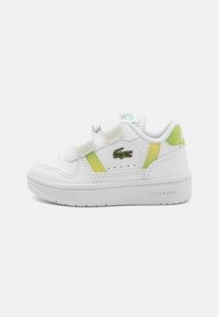 Baskets en cuir blanches avec des accents jaunes, bandoulières Velcro et un logo. Semelle texturée et partie supérieure lisse, avec des détails de couture minimalistes.