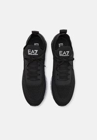 Svarta sportskor med övre i mesh och syntetmaterial, texturerade detaljer och vit logotyp på tungan. Flexibel sula för ökad komfort.