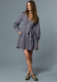 Röd och blå rutig klänning med lång ärm och ett knytbälte, med v-ringning och fickor. Kombinerad med olivgröna balettskor.