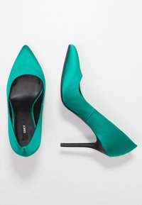 Tyrkysové saténové vysoké podpatky s špičatou špičkou a elegantním černým koženým interiérem. Disponují stiletto podpatkem a minimalistickým designem.