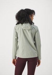 Lichtgroene, gewatteerde jas met een gladde textuur en lange mouwen, gecombineerd met donkerburgundy leggings. Minimalistisch ontwerp.