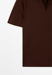 Kortärmad brun polo med en texturerad finish och en delad V-ringad design, med rena sömmar och rakt avslut.