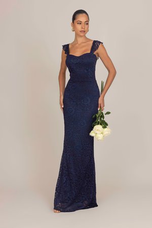 Robe de soir en dentelle navy avec une silhouette ajustée, col carré et bretelles en dentelle. Le mannequin tient des roses blanches, sur un fond neutre.