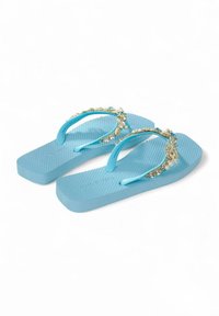 Flip-flops azules con suela texturizada y correas decorativas que presentan acentos dorados y perlas. Diseño plano con sujeción entre los dedos tipo tira.