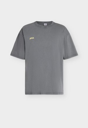 Grå unisex t-skjorte med korte ermer, rund hals og liten gul "ARKK" logo på øvre venstre bryst.