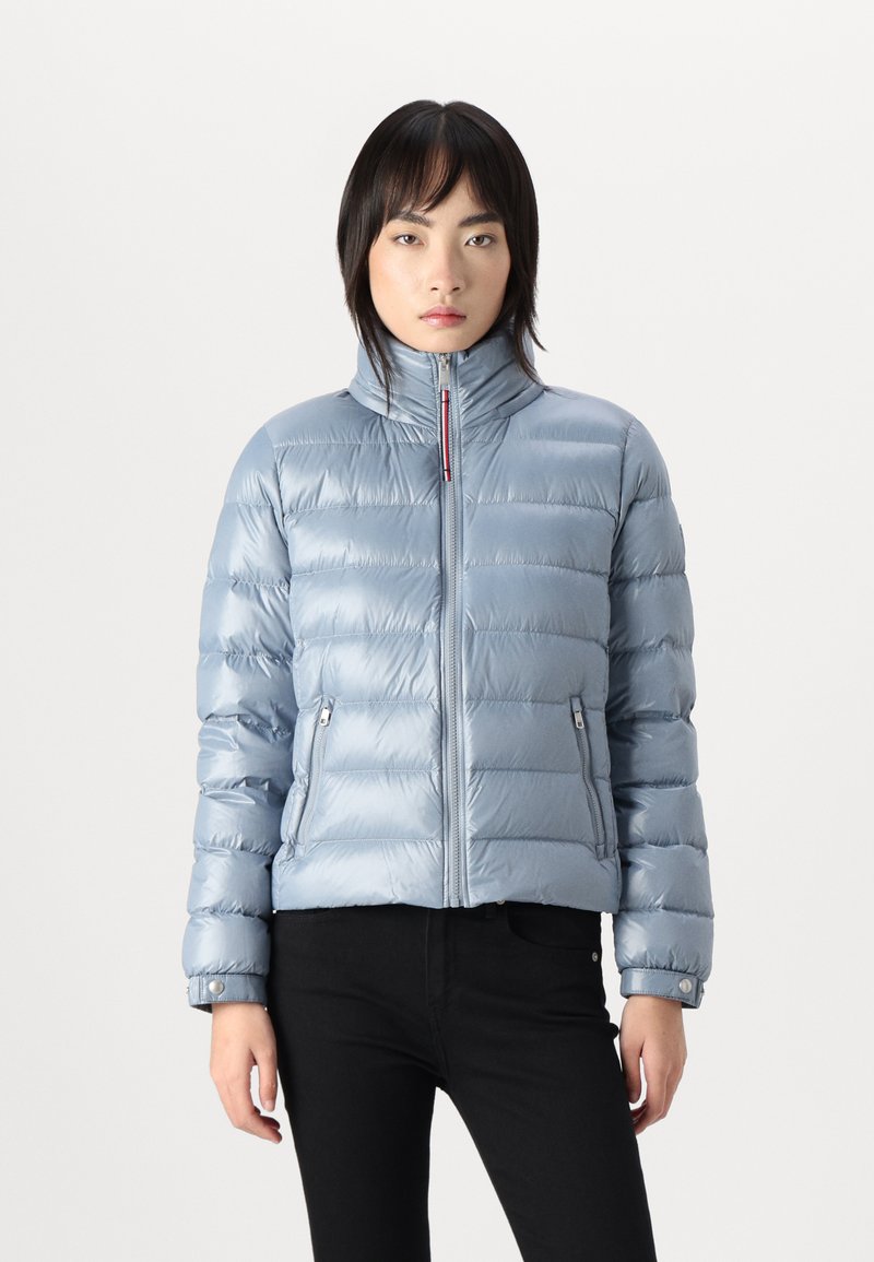 Lyseblå pufferjakke med quiltet design, høy krage, glidelås foran og sidelommer. Glatt, blank overflate, cropped lengde.
