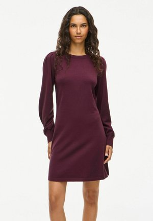 Robe en tricot bordeaux avec manches longues, encolure arrondie et détails froncés aux épaules. Texture lisse et coupe décontractée au-dessus du genou.