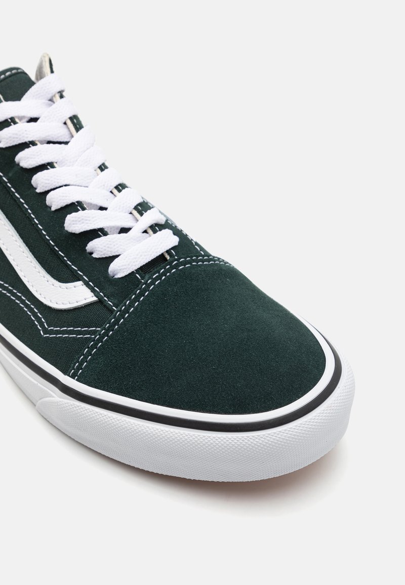 Groene suède sneakers met witte veters, zwarte accenten en een gestructureerde rubberen zool. De stiksels omlijsten het ontwerp van de schoen.