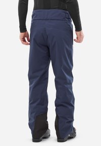 Pantalons de ski imperméables de couleur marine avec une coupe ajustée, dotés d'une taille haute, de panneaux noirs renforcés aux chevilles et d'un tissu durable.