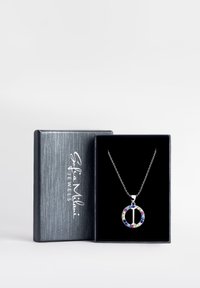 Sølv halskæde med en cirkulær vedhæng prydet med farverige sten i forskellige nuancer, præsenteret i en sort fløjlæslet boks.