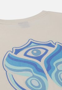 Crème katoenen t-shirt met blauwe abstracte borduring in een spiraalontwerp en een oogmotief, ronde hals en korte mouwen.