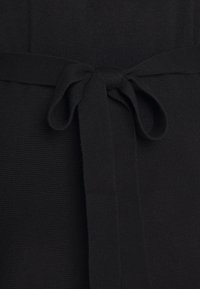 Tissu en maille noire avec une finition texturée, doté d'une ceinture nouée à la taille. Le design comprend des lignes espacées régulièrement et une apparence douce.