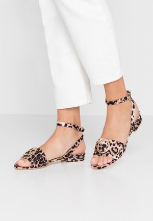 Flade sandaler med leopardprint og ankelrem, med en cirkulær metalaccent foran og en struktureret stofoverflade.