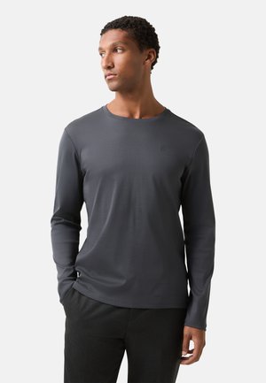 Long-sleeve, crew neck shirt in dark gray, made of a smooth fabric. Features a small logo on the chest and fitted design.