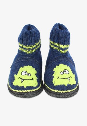 Blue knitted slippers with green monster faces, featuring ribbed ankles and yellow stripes. The soles are black and textured for grip.