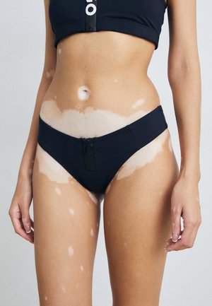 Black swim bikini with a front zipper detail. Made of smooth, elastic fabric. Minimalist design with a low-rise cut.