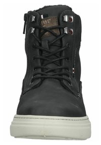 Zwarte leren enkellaars met metalen veterogen en vetersluiting. Heeft een witte rubberen zool en een bruine textiele accent op de tong.