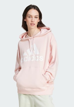 Felpa rosa con logo "adidas" bianco, cappuccio con cordino, tasca frontale e polsi a costine. Tessuto morbido con una vestibilità rilassata.