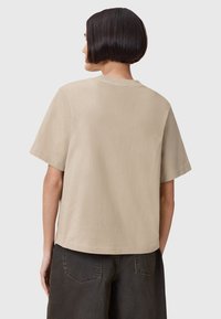 T-shirt in cotone beige con vestibilità comoda, maniche corte e design posteriore semplice. Tocco morbido e stile semplice, senza decorazioni.