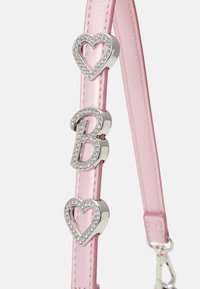 Bracelet rose avec des breloques argentées ornées de strass en forme de deux cœurs et de la lettre "B", attaché à un fermoir métallique.
