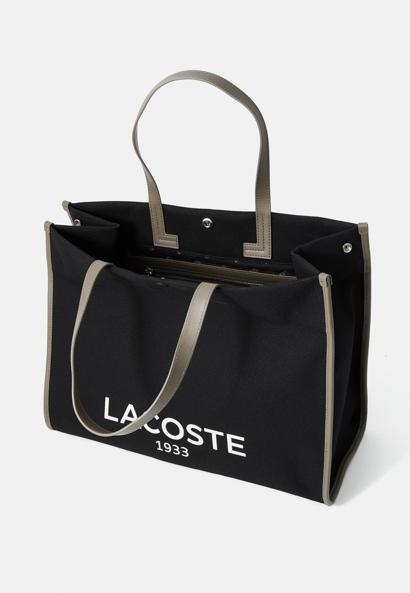 Borsa a tracolla nera in canvas con accenti in pelle sintetica grigia, dotata di due manici, tasca interna con zip e testo del logo bianco sul davanti.