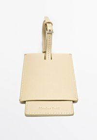 Beige leren bagagetag met een gladde textuur, een lusriem en geperste "Massimo Dutti" branding onderaan.