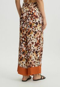 Lange, luchtige rok van gladde stof, met een luipaardprint in oranje, bruin en crème, met een oranje zoom en een elastische tailleband.