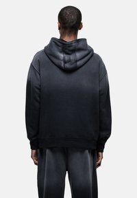 Felpa con cappuccio nera sfumata, dotata di un ampio cappuccio regolabile. Presenta polsini e orlo a coste, realizzata in un morbido tessuto testurizzato, che evidenzia un taglio comodo.