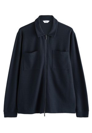 Veste zippée bleu marine en tissu texturé, avec un col à revers et deux poches avant. Design minimaliste avec manches longues.