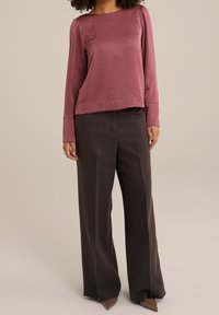 Dlouhý rukáv mauve top s lodními výstřihem, spárovaný s přizpůsobenými tmavě hnědými širokými kalhotami a béžovými lodičkami s špičatou špičkou. Hladká textura po celé ploše.