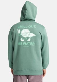 Hoodie verde menta con cappuccio regolabile, caratterizzato da una grafica giocosa sul retro che recita "CALMATI. SII ACQUA" con arte in stile cartone animato.