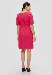 Robe rose à manches courtes avec une silhouette ajustée, dotée d'une fermeture éclair au dos et d'une fente à l'ourlet pour faciliter le mouvement. Texture lisse.