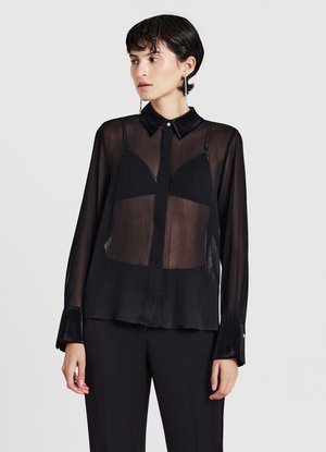 Blusa nera trasparente a maniche lunghe con colletto classico, placca dei bottoni nascosta e dettagli in velluto sui polsini. Presenta un design semitrasparente.