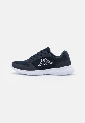 Zapatilla deportiva negra con suela blanca y logo de dos figuras sentadas en el lateral, mostrada de perfil sobre un fondo claro y liso.