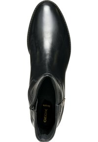 Botte de cheville en cuir noir avec un bout rond, texture lisse, fermeture éclair sur le côté et un détail de logo subtil à l'intérieur. Design élégant avec des accents minimalistes.