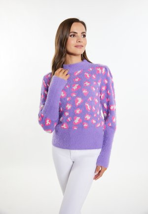Maglione viola peloso con macchie leopardate rosa e bianche, caratterizzato da un collo alto e maniche lunghe, abbinato a pantaloni bianchi. Texture morbida.