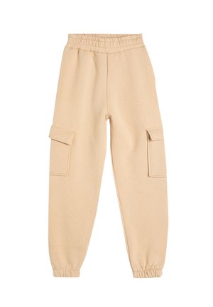 Pantalons de jogging beige avec une texture douce, une taille élastique et deux poches cargo latérales. Les poignets aux chevilles créent une coupe fuselée.